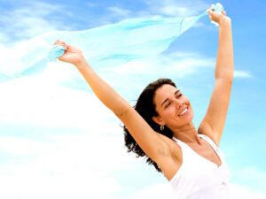 woman happily runs outside holding a scarf over her head