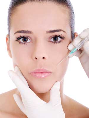 woman with dark hair and a botox injector near her face